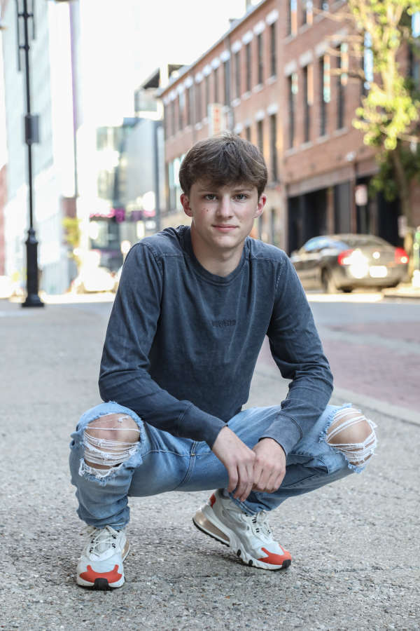 Young man crouching on sidewalk